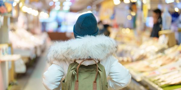 Person wearing a winter coat and backpack in a market.