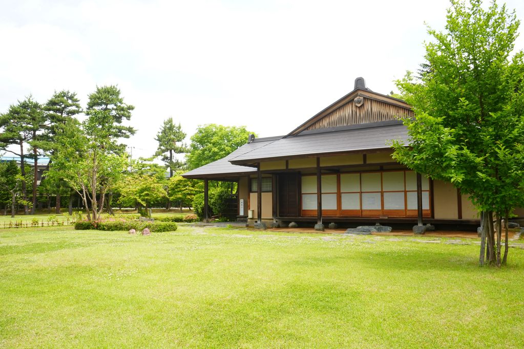 Traditional Japanese house surrounded by a green garden and trees.