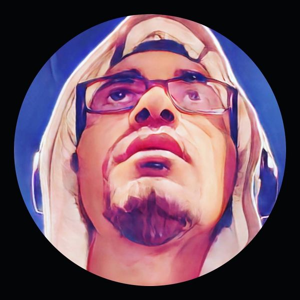 Artistic close-up portrait of a man wearing glasses and a hood.