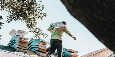 A man carrying roofing materials on a residential roof
