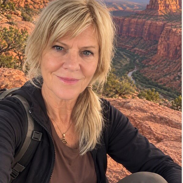 Woman taking a selfie in a canyon with river and rock formations.