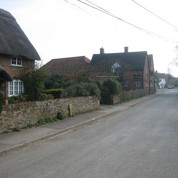 A quiet street with brick houses and a stone wall in a rural village.