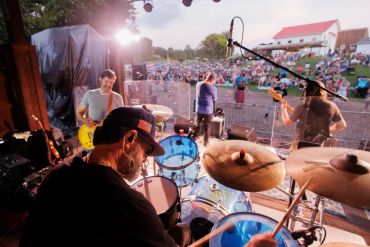Band performing live on outdoor stage at sunset.