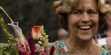 Smiling woman holding a vibrant bouquet of flowers.