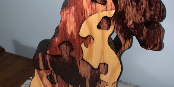 Wooden dinosaur puzzle with interlocking pieces in natural and stained wood tones.