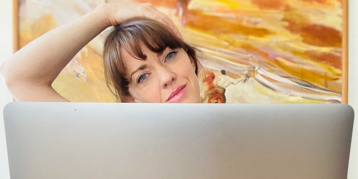 Woman stretching neck behind computer and smiling - workplace movement, occupational health