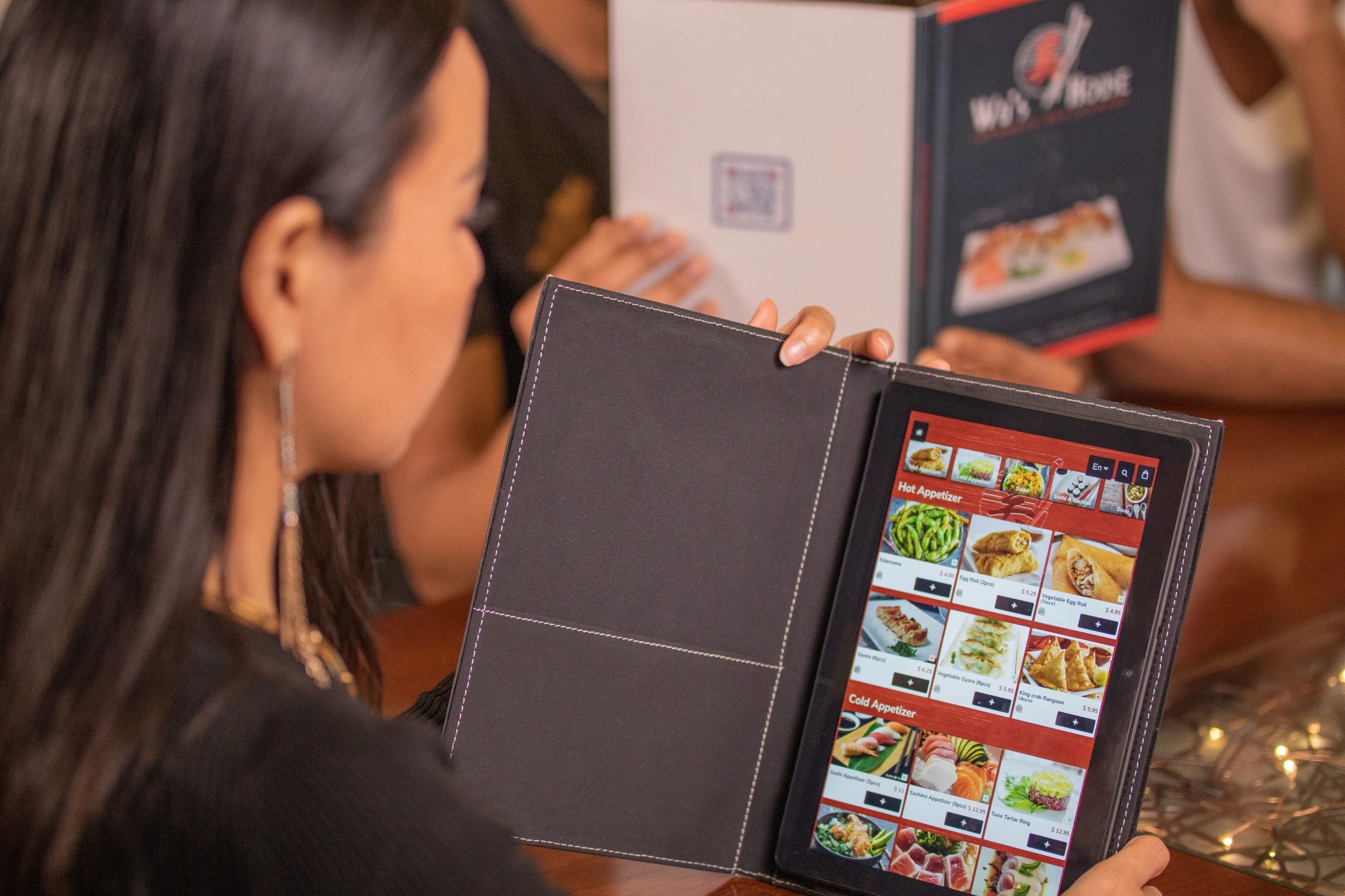 Beautiful Asian woman holding a Smart Tech Menu "Digital Tablet Menu" at a restaurant.