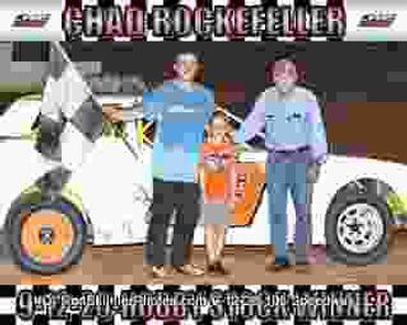 Three people stand with a race car, celebrating a win.