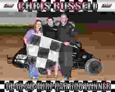 Race winner Chris Russell celebrates with team and checkered flag.