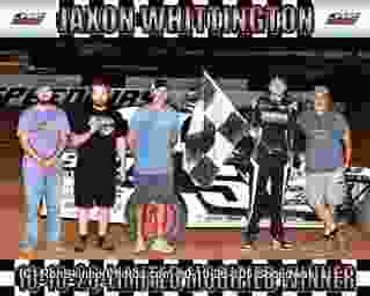 Group of men posing with a race car and a checkered flag.