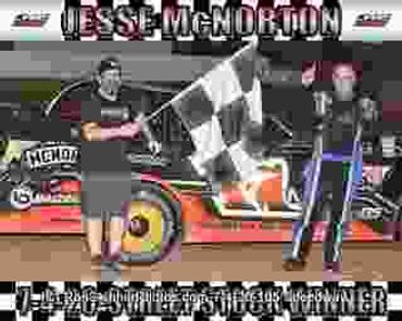 Race car winner celebrating with flag and another person.