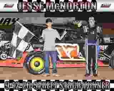 Two people standing near a race car with a checkered flag.