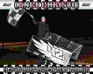 Race car driver celebrating victory with checkered flag.