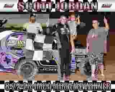 Four people posing next to a decorated race car at night.