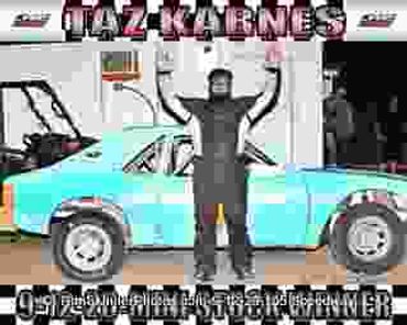 Man standing with arms raised beside blue car.