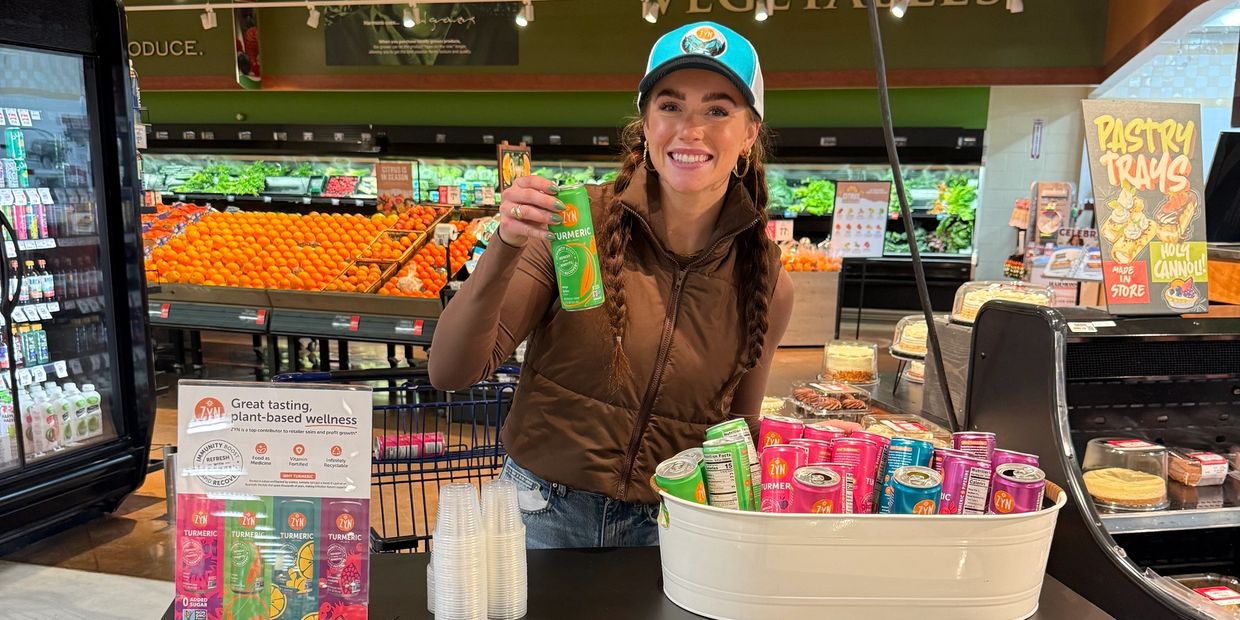 Thomas & Hobbs Marketing brand ambassador sampling a turmeric wellness drink in the produce section 