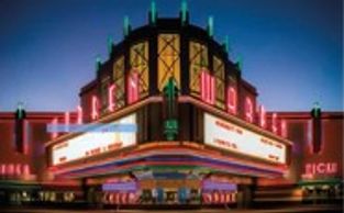 A neon-lit vintage cinema at night with a glowing marquee.