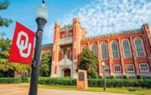 University building with Oklahoma flag and blue sky.