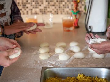 roti dough on a table and hands holding balls of roti dough