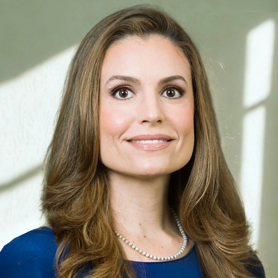 Professional woman with long hair and pearl necklace smiling.