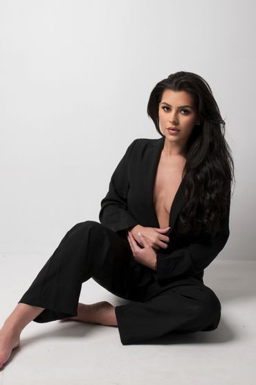 Woman in black suit sitting on the floor.