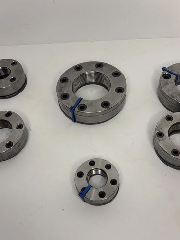 Metal circular flanges with bolt holes and blue markers on a white surface.