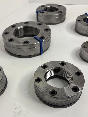 Metal threaded rings with bolt holes arranged on a white surface.