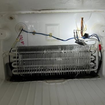 Freezer evaporator coil with wiring and frost buildup.