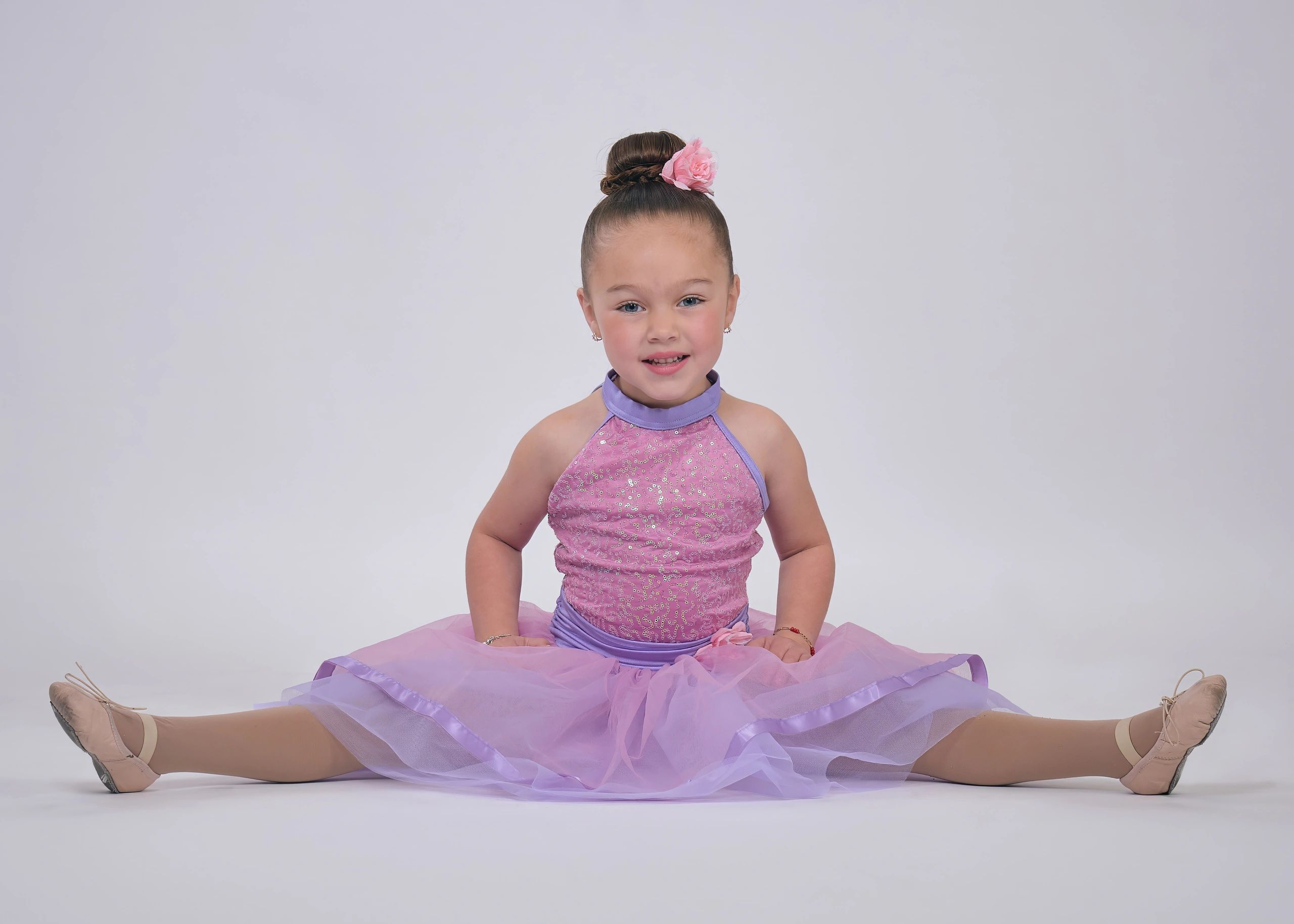 Young ballerina in a purple dress doing a split.