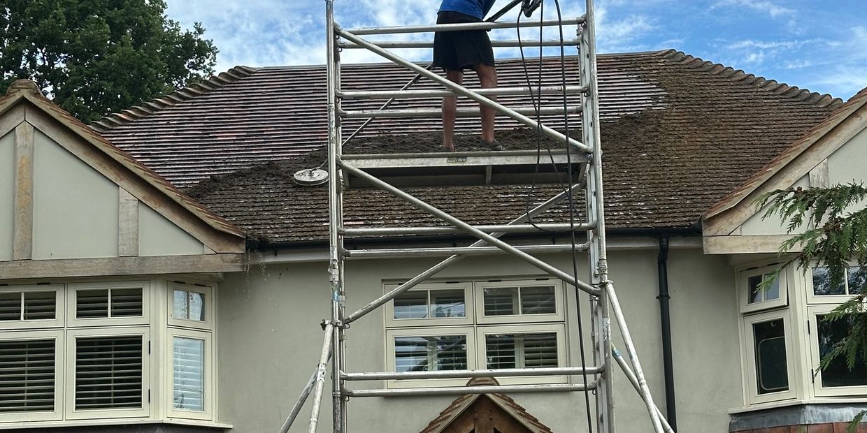 Worker cleaning roof on scaffolding.