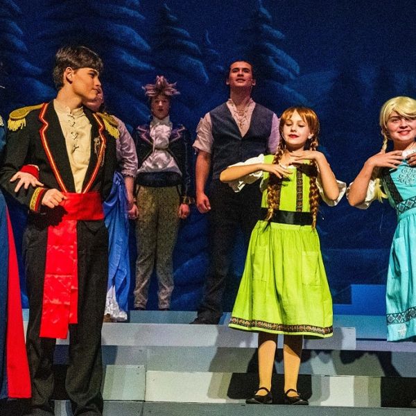Actors performing a lively scene in colorful costumes on stage.