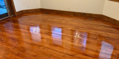 Shiny wooden floor reflecting window light in an empty room.