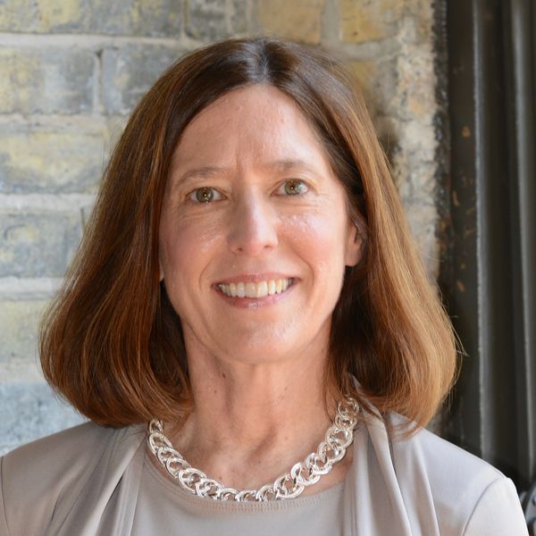 Smiling woman with shoulder-length brown hair and a silver necklace.
