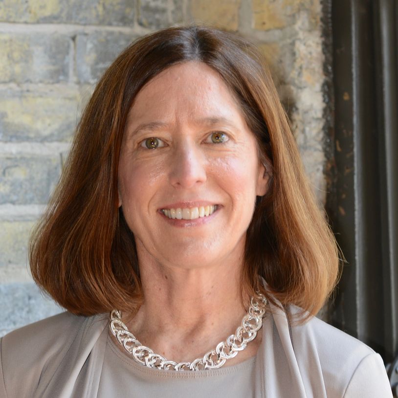Smiling woman with shoulder-length hair and a silver necklace.