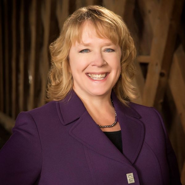 Smiling woman in a purple blazer.