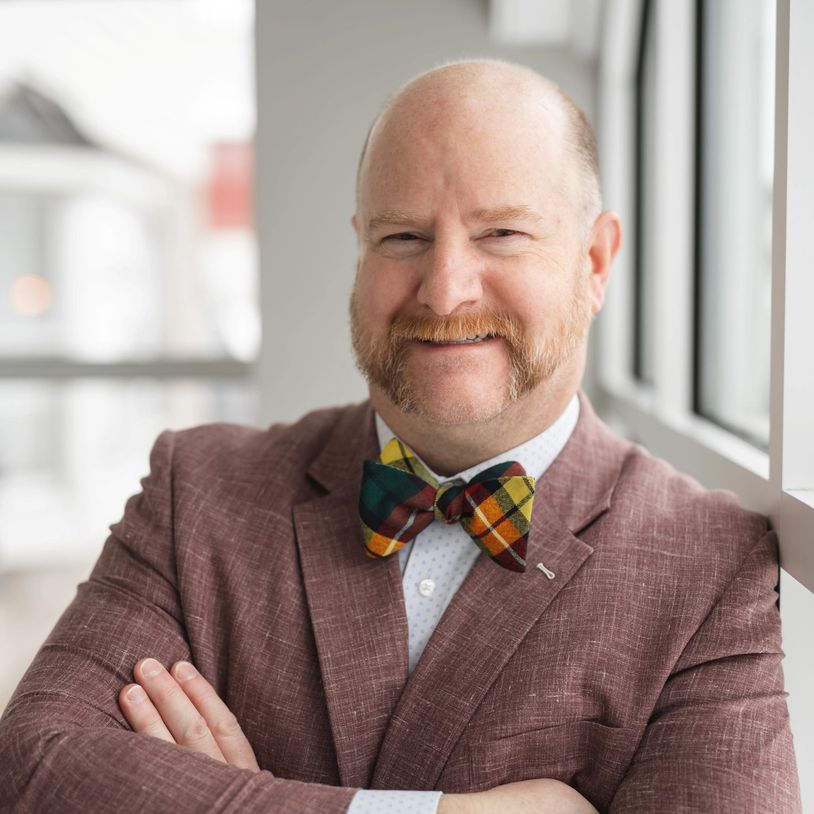 Smiling man with a colorful bow tie and sideburns.