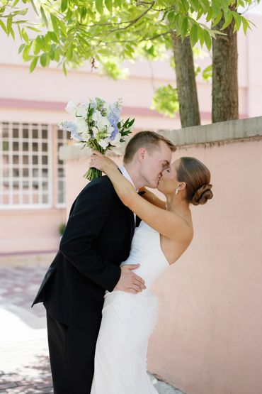 Bride and groom kissing outdoors on wedding day.