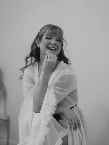 Black and white portrait of a smiling woman in a sheer dress.