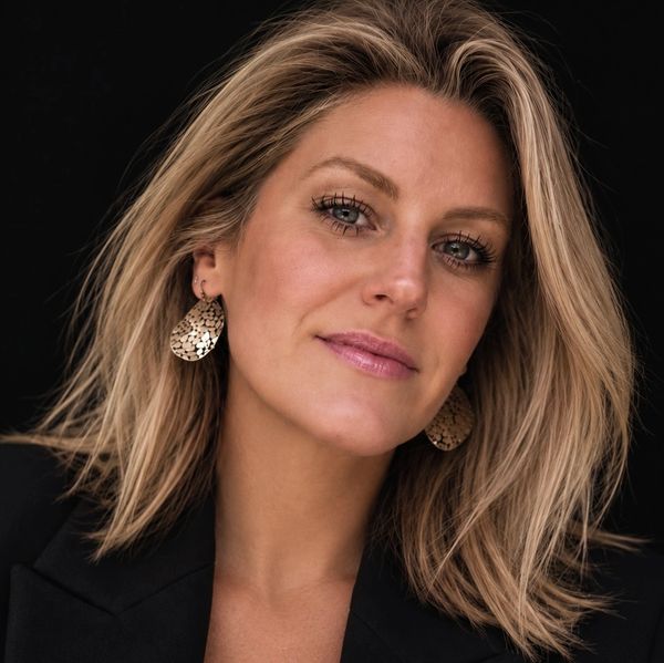 Portrait of a confident woman with blonde hair and statement earrings.