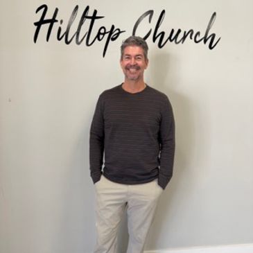 Man standing in front of Hilltop Church sign.