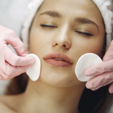 woman getting her face cleaned with cotton rounds 