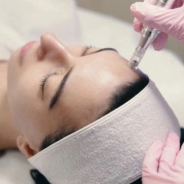 Woman receiving facial with a special device for collagen induction therapy  