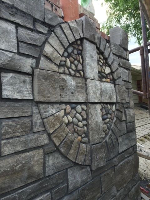 Decorative stone wall with circular design and embedded stones.