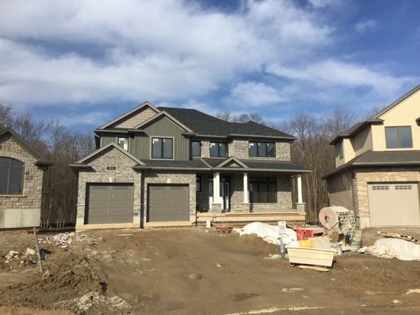 Newly constructed two-story house with an unfinished driveway and surrounding construction materials.