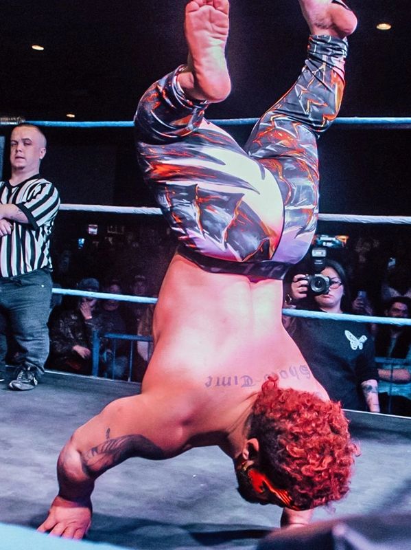 Wrestler balancing upside down on hands in the ring.