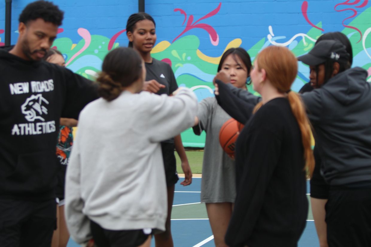 Group bumping fists on a basketball court.