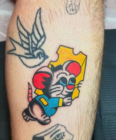 Colorful tattoo of a mouse and bird on a leg.