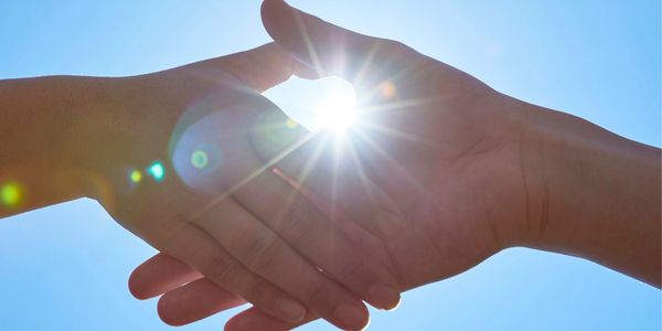 Two hands forming a heart shape with sunlight shining through.
