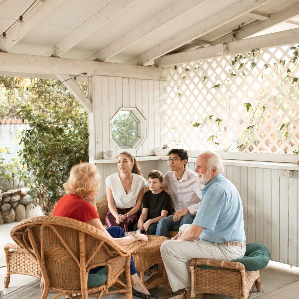 Three generations of neighbors gather on a shady porch to talk.