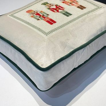 Side view: needlepoint canvas inset into a fabric frame with contrast welt and gusset (boxed pillow)